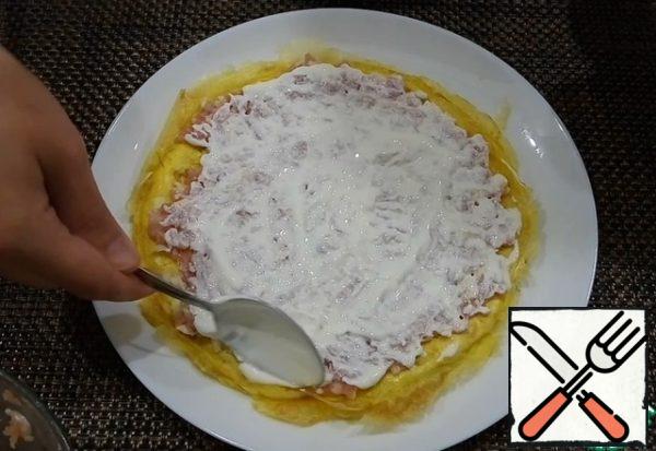 Minced meat divided into three parts. Prepare the sauce, in sour cream, squeeze the garlic and mix well. Sour cream can be replaced with mayonnaise. For each pancake, distribute the minced meat over the entire surface and grease it with sour cream-garlic sauce.
