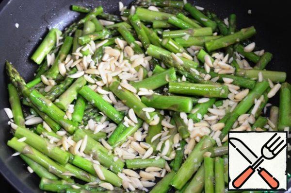 Add the nuts to the asparagus and fry for another 3-4 minutes (under the lid).
