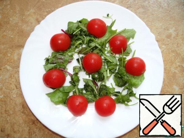 Chop the greens coarsely, put them in a bowl, add the tomatoes, cut in half.
