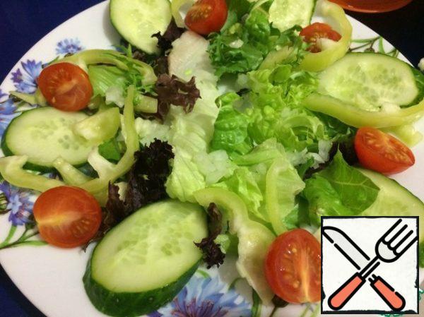 Put a pillow of lettuce leaves on a plate, sprinkle onions on top, arrange cucumber, pepper, tomatoes.
