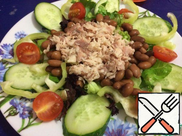 Then spread the beans in a circle, and put the tuna in the center.
Put a pillow of lettuce leaves on a plate, sprinkle onions on top, arrange cucumber, pepper, tomatoes.
