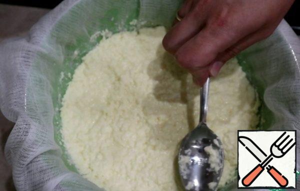 Cover the colander with gauze folded in several layers and carefully lay out the cottage cheese, press down well with a spoon, forming a shape of cottage cheese. Leave to stand on the table for 1 hour to get the serum.
