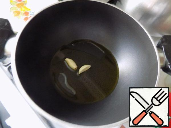 In a saucepan poured olive oil, warmed it and put a clove of garlic, cut in half. Fried it for a minute, so he gave his flavor oil and removed it from the pan (threw).
