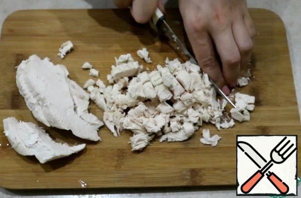 Boil chicken fillet in salted water, cool and cut into small pieces.