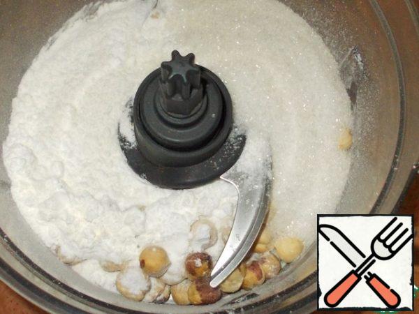 Prepare the dry component for our cake. In the processor bowl mix 150 g of hazelnuts, flour, 70 g of granulated sugar and powdered sugar.