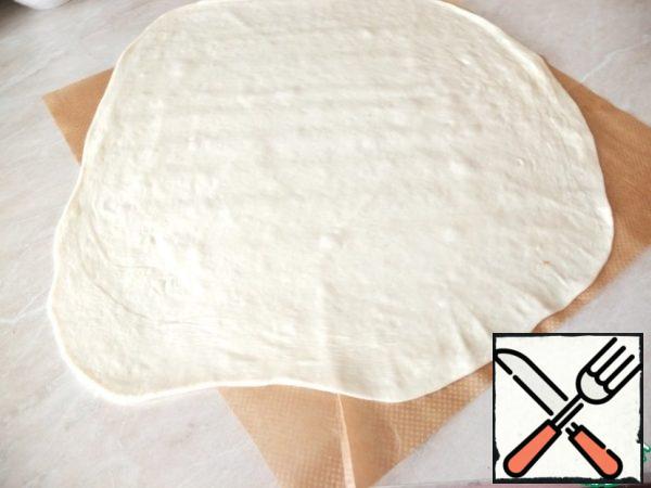 Since the dough will have to roll out as thin as possible, I did it immediately on parchment. Additionally sprinkle with flour is not needed.
Roll out the dough thinly.