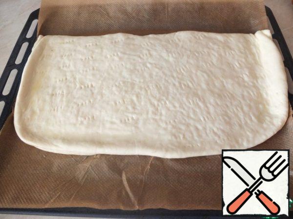 Cover the second part, carefully pinch the edges and roll out again as thin as possible.
Prick the cake with a fork, grease with a slightly beaten egg.