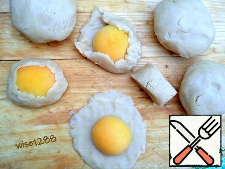 Put the oven to warm up to 180 degrees. Each quarter of the dough cut into four parts and roll the cakes, in the middle of which lay half apricot. The edges of the dough to raise and press to the apricot and form a cookie so that the middle of the apricot was open.