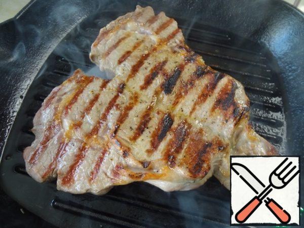 After 3 minutes, brush the meat with olive oil, season with salt and pepper and turn it over to the other side.
