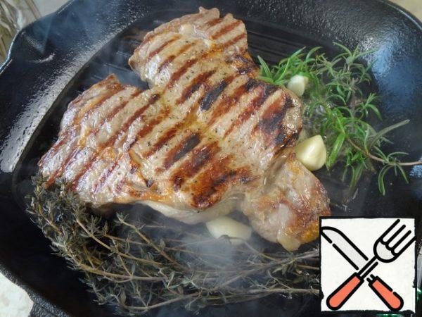 After another 2 minutes throw a piece of butter, rosemary, thyme and garlic. At this point, the oil melts, absorbs the aromas of herbs and garlic, passes them to the meat. Do not be afraid of gray thyme, it was frozen in a vacuum bag, its flavor is preserved, but the color faded.