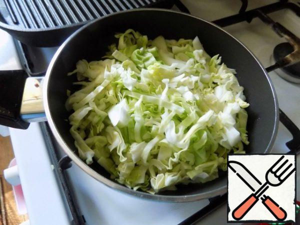 Prepare the filling for the cake. Pour sunflower oil into a saucepan, heat it up and put the crushed garlic clove with the flat side of the knife. Fry it for a minute until the garlic gives its flavor to the oil. Take out the garlic and put a coarsely chopped onion. I used a white onion. You can take any one. Gild the onion for a couple of minutes and lay out the chopped young cabbage. Cabbage can be fried to your liking. I don't fry almost anything. Boil the cabbage until soft. It's fast, in 5 minutes. It's in the pie.
