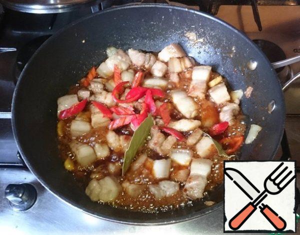 When the meat slightly fried (browned, but the inside is still raw of course), add the soy sauce, hot pepper and Bay leaf.
Continue roasting, made by boiling down soy sauce. The liquid should remain, do not evaporate to "dry frying pan", this is quenching, not hot.