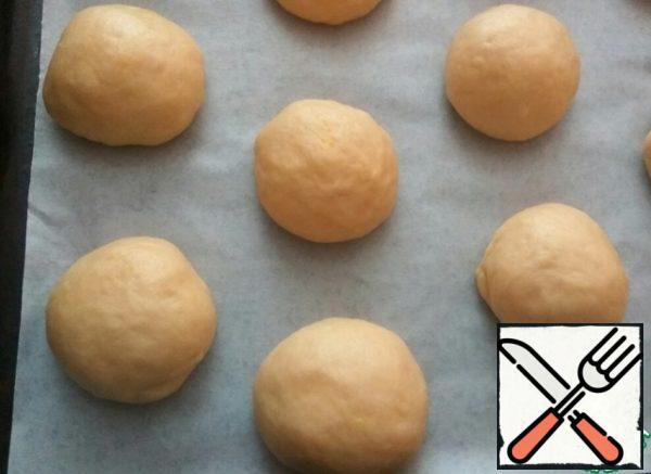 Beat the risen dough and divide into 12 parts. Roll the balls.
Place on a baking sheet covered with parchment, at a distance from each other.
Leave it on for 15 minutes.