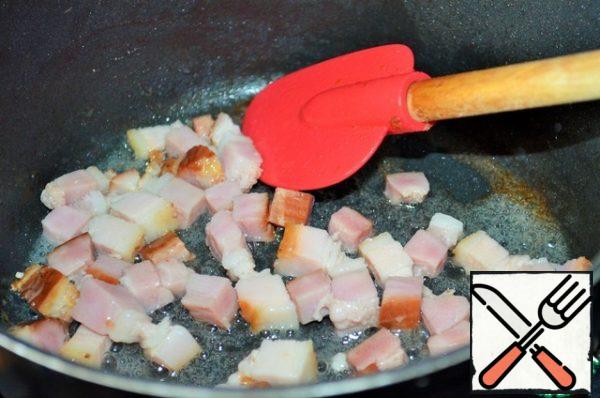 In a pot or deep saucepan heat the oil,
fry the pieces of bacon on it.