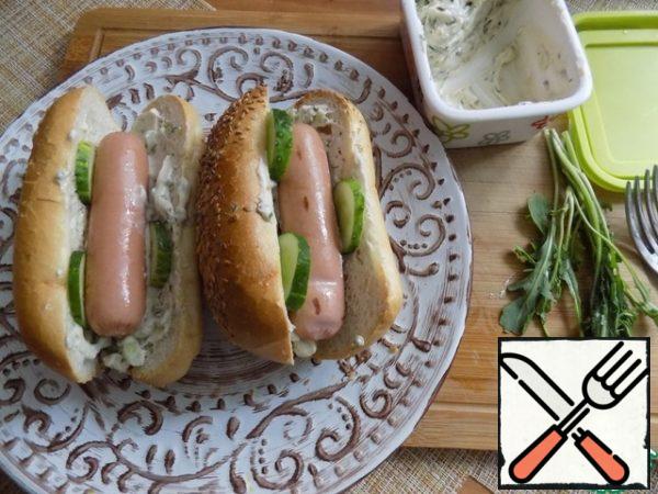Sausages are placed in a bun. Cucumber remaining cut into thin slices, the arugula leaves break off. Put slices of cucumbers between sauce and sausage.