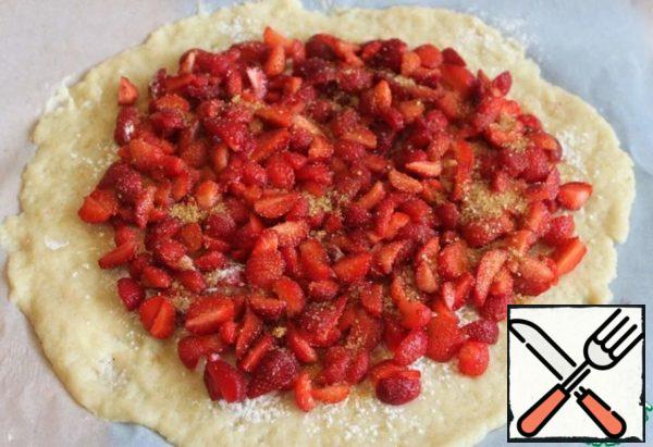 The strawberries into quarters. Spread strawberries, retreating from the edge of about 2 cm. Sprinkle with two tablespoons of sugar.