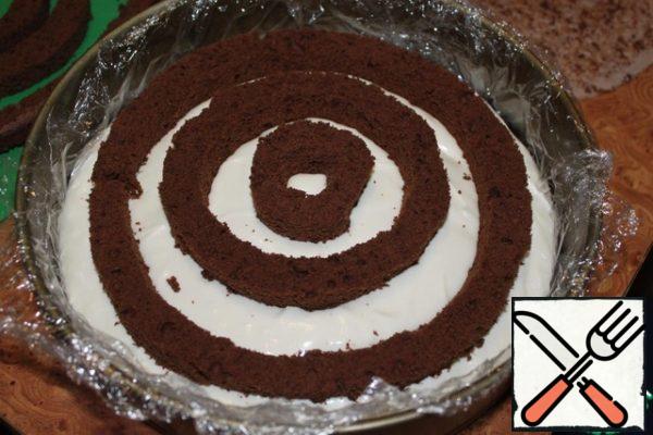We cover the split form with cling film, put our cut-off top there. Lubricate our "top" with cream, spread the first layer of "sponge circles".
