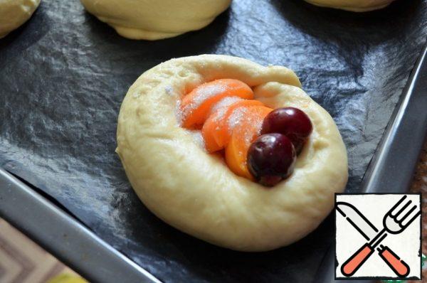 Turn on the oven for heating.
In the middle of the workpiece pour 1/2 tsp starch ( can be potato), put the pieces of apricot and 2 cherries, sprinkle with sugar.
Grease the spaced blanks with a mixture of yolk and cream and place in the oven.