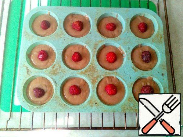 Next, we put pre-washed strawberries in the center of each cake. Then send the mold to the preheated oven and bake for 25-30 minutes at a temperature of 200-220 degrees.
