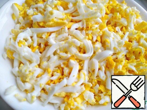 Boil hard-boiled eggs, peel, grate on a coarse grater.
