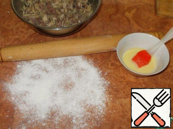While we were engaged in cutting the dough, the minced meat had time to brew and you can start forming samsa. Prepare the yolk to lubricate the blanks by mixing it with a tablespoon of water. Sprinkle the table with flour and a rolling pin.
