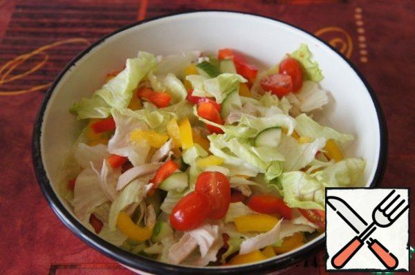 Wash the salad, dry it and cut it into pieces by hand. Cut the cucumber into triangular slices, tomatoes in half or quarters (depending on their size), peel the pepper from the core and cut into strips. Mix all the vegetables carefully in a wide bowl.
