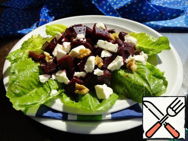 Put the lettuce leaves on the dish, and put the beetroot in the marinade on top. Crumble the pieces of feta with your hands. And we finish with walnuts. Pour over the marinade.