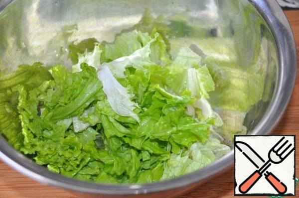 Lettuce leaves are washed, dried, cut or torn, put in a bowl.
