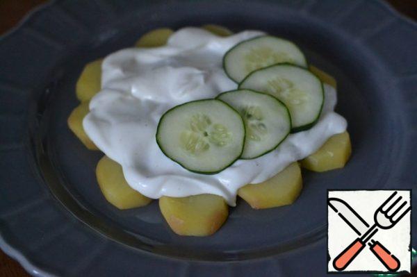Spread half the sauce on the potatoes.
On top lay a row of slices of cucumber .