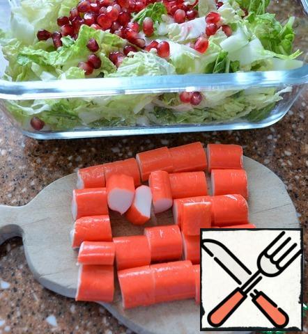 Pour olive oil over the grains and mix,
thus they will not let the juice and not paint the salad stains.
Add pomegranate seeds to the cabbage.
Crab sticks cut into large.