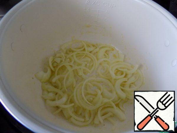 Pour olive oil into a slow cooker pan, turn on the baking mode. Spread the onion, cut into half rings. Olive oil can be replaced with sunflower oil.

