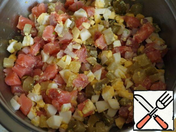 Cut the fish fillets into cubes.
Do the same with cucumbers, eggs and onions.
Put everything in a salad bowl and mix.

