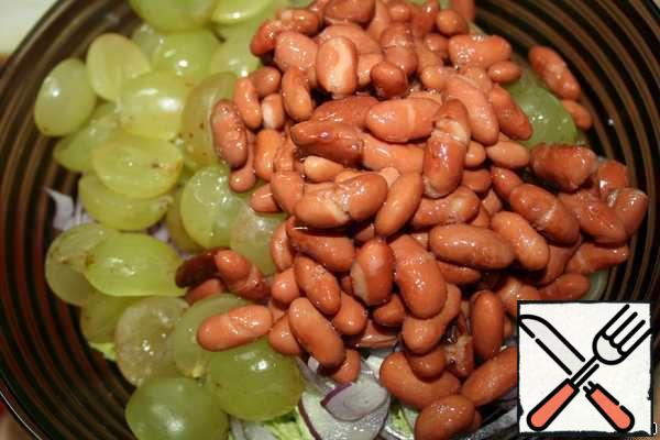 Wash the grapes, dry them and cut each berry in half, if the grapes have pits, then remove them. Beans are thrown into a colander. Add to the cabbage and onion.
