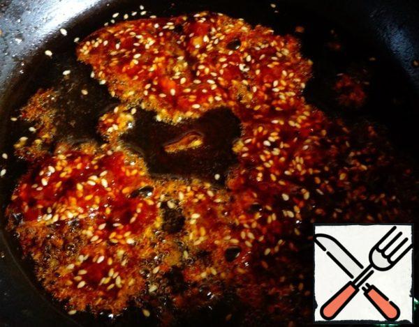 In the remaining oil, dissolve the sugar to a caramel state (so that the color changes to a pleasant caramel), pour sesame seeds into it.
