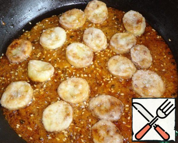 Put the fried bananas in the caramel and mix well. Chopsticks (or fork / spoon), which you will use to remove bananas from the mold, hold in cold water so that the caramel does not stick to them. Take each piece and dip it in water, and then put it on a plate to solidify.
Put the bananas on a plate and let them cool.
