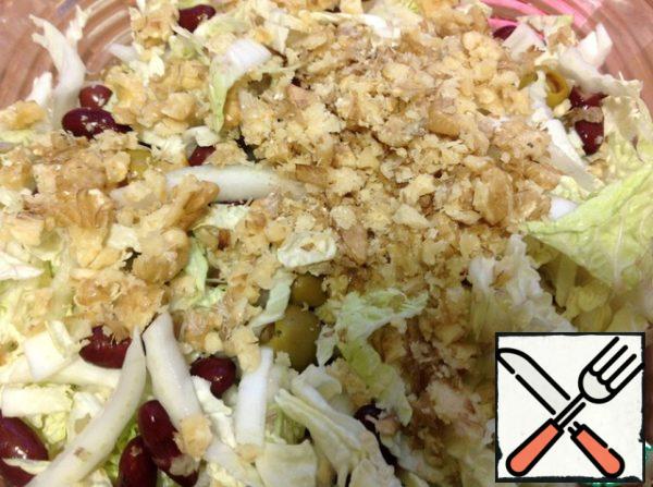 Roll out the nuts with a rolling pin, not very finely, and add to the salad, as well as salt, sugar, oil and vinegar, mix and add pepper very carefully, someone will need a smaller amount.
