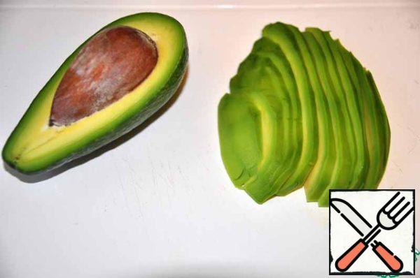 Take a ripe, but not soft avocado, cut in half, turn the halves against each other, separate the bone, clean, cut along into thin strips.