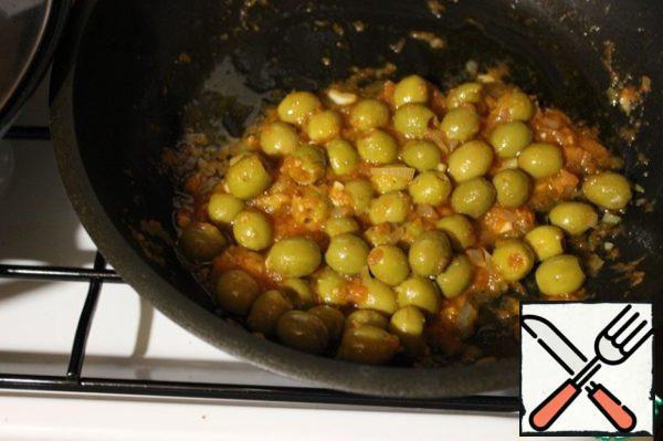 Pour olive oil into a frying pan and fry the finely chopped onion over medium heat for 5 minutes, reduce the heat, add the finely chopped garlic and cook for another 2-3 minutes. Peel the tomato, grate it on a fine grater, add to the onion along with sugar, spices, 1 teaspoon of olive liquid and simmer over low heat for 7-10 minutes. Pour boiling water over the olives, drain the water and put it with the vegetables. Close the lid and simmer, stirring occasionally, for 12-15 minutes. Add salt and cook for another 3 minutes.
