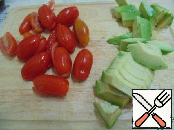 The cherry tomatoes cut into halves, the avocado cubes.