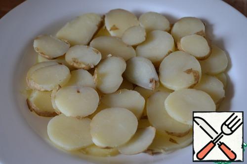 Potatoes cut into slices. Put on a flat dish.