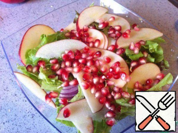 Put in a salad bowl lettuce, onions, apples and add a handful-two pomegranate seeds.