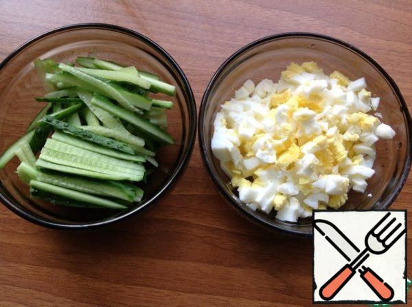 Cut cucumbers into strips, chop eggs in a separate bowl.
