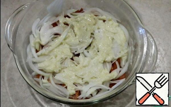 In a baking pan put the pork, then the onion. Grease with Béchamel sauce, about 2-3 tablespoons.