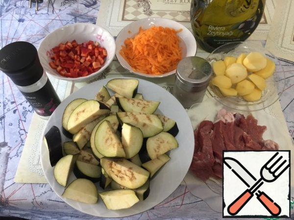 Prepare all the ingredients. Cut the meat into strips. Grate the carrots on a grater. Cut the potatoes into cubes. Eggplant - half of the circles. Grind the bell pepper.