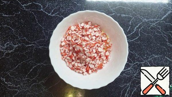 Put the chopped eggs and crab sticks in a large container.
