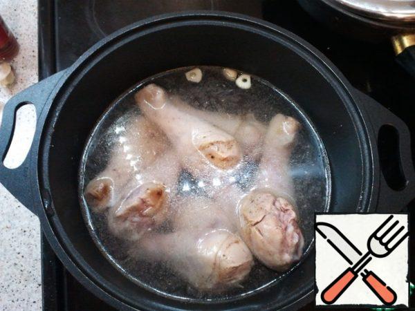 With a knife, make cuts and put there garlic pre-cut (2 cloves enough), then put everything in a pot, the water should cover the chicken and cook for at least 50 minutes.