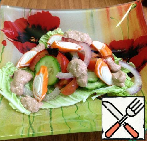 In a bowl tear a bit of lettuce, put the lettuce, decorate crab sticks and cover with sauce.