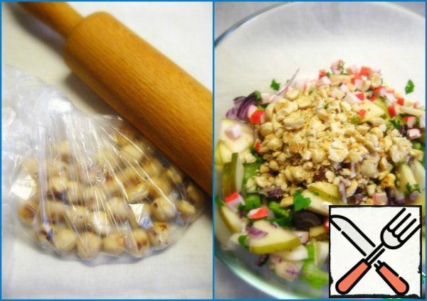 Fold the nuts in a package and rolled with a rolling pin. Add the chopped nuts to the salad bowl.