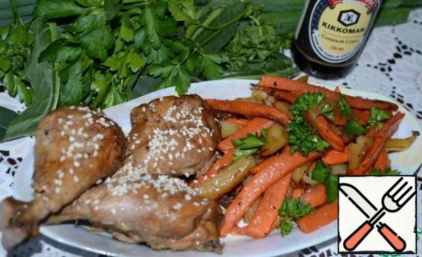 Vegetables are served with chicken drumsticks sprinkled with sesame seeds and herbs.