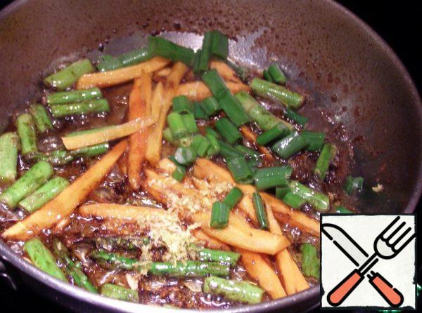 Chop the asparagus, finely chop the carrots into strips, three ginger and fry the whole vegetable sliced in olive oil with soy sauce and 2 tablespoons of orange juice for 5 minutes, stirring constantly. Chop the green onion and add it at the end of frying for 1 minute.
